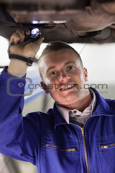Mechanic illuminating the below of a car