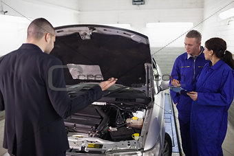 Client looking at a car next to mechanics