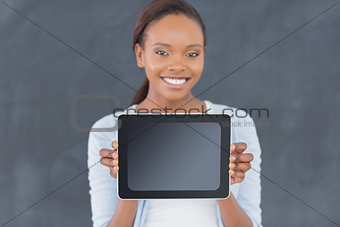 Black woman holding a tablet computer next to a blackboard