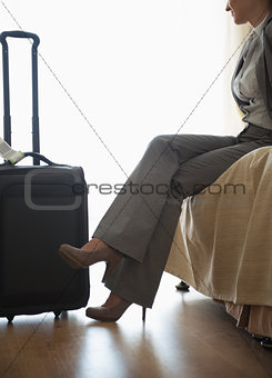 Tired business woman sitting on bed in hotel room after trip