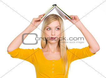 Confused student girl with raised book over head