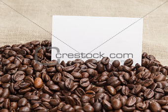 heap of coffee beans on burlap with card