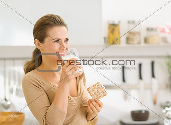 Young woman eating crisp bread with milk and looking on copy spa