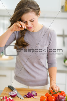 Young housewife crying while cutting onion