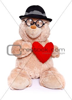 Teddy bear wearing hat holds red heart