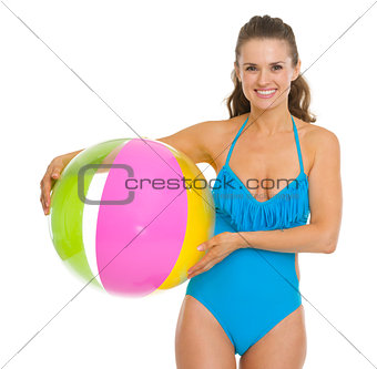 Smiling young woman in swimsuit holding beach ball
