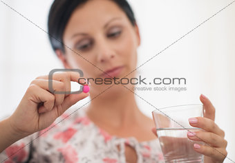 Closeup on pill and glass of water in hand of concerned young wo