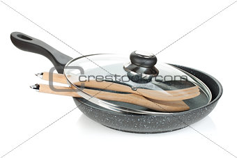 Frying pan with glass cover and wooden utensils