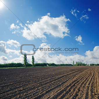 black plowed field under blue sky with sun