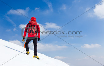 Mountaineer walking uphill along a snowy slope.
