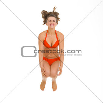 Happy young woman in swimsuit jumping in water