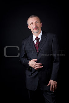 Mature businessman holding hand on his black suit
