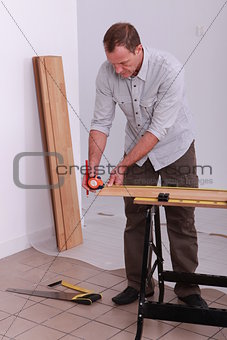 handyman measuring a wooden board with a measure-tape