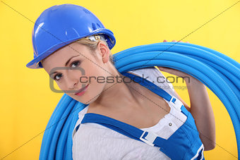 Blond plumber carrying plastic piping