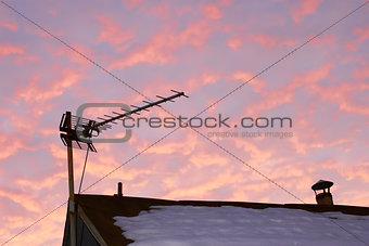 TV antenna against reddish cloudy sky