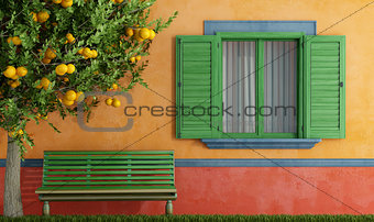 Old house with green  windows bench and tree