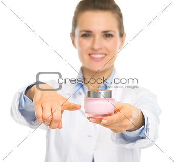Smiling cosmetologist woman pointing on creme