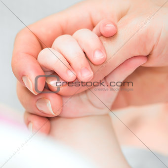 baby holds mother's finger