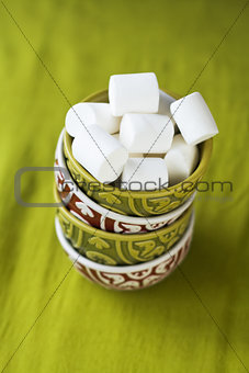 Four oriental national bright bowls on a green background and white marshmallows