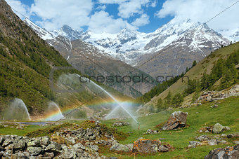 Rainbows in irrigation water spouts in Summer Alps mountain 