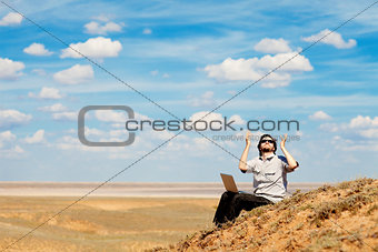 man with laptop praying to the God
