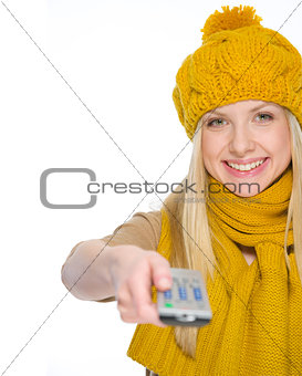 Happy girl in autumn clothes using tv remote control