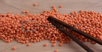 Raw red lentil on a wooden plate with sticks