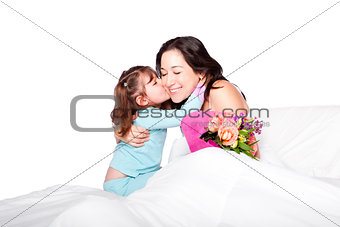 Child gives flowers and kiss to mom in bed