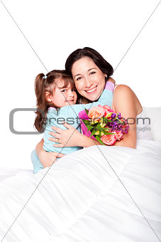 Child gives flowers to mother in bed