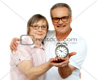Aged couple with alarm clock on plam