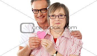Matured smiling couple holding paper heart