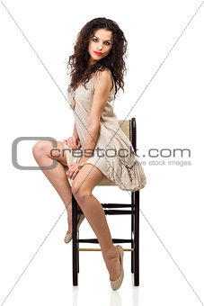 Young woman in linen dress sitting on tall chair
