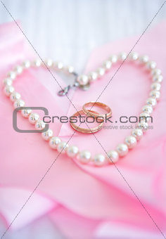 Two wedding rings on the pink background with pearl