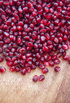 Pomegranate seeds on a wooden board
