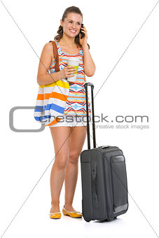 Young tourist woman with wheel bag talking mobile phone