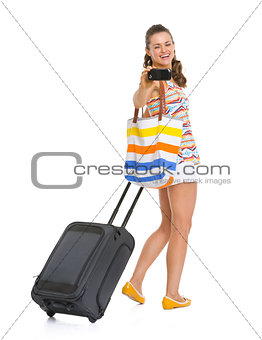 Happy young tourist woman with wheel bag taking photos with cell