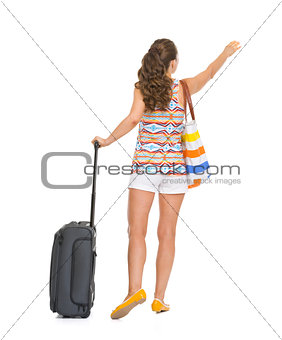 Full length portrait of tourist woman with wheel bag catching ta