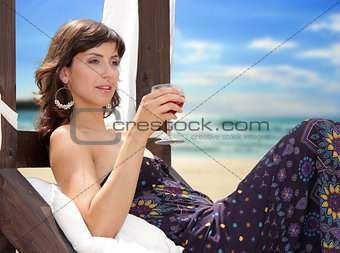 Young woman with a drink on the beach enjoying a cocktail.