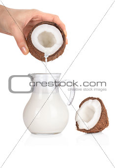 Woman's hand pouring coconut milk into a jar isolated on white b