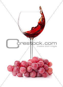 Splashing red wine in a glass and grapes