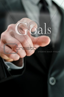 Male hand pointing at Goals icon on a touch screen interface