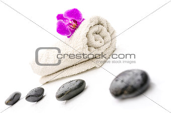 Massage stones and violet orchid flower on a towel