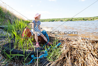 small girl on the bank of river with rubbish