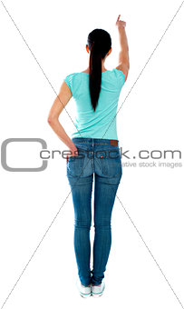 Rear view of young woman in casuals, pointing