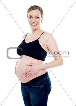 Smiling pregnant woman caressing her belly