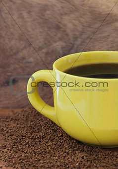 Yellow mug with coffee on the table with a instant coffee granul