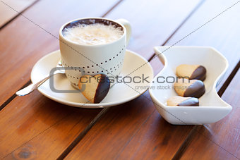 Freshly baked heart-shaped cookie and cappuccino