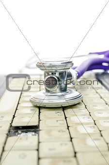 Stethoscope on and old laptop keyboard missing a key
