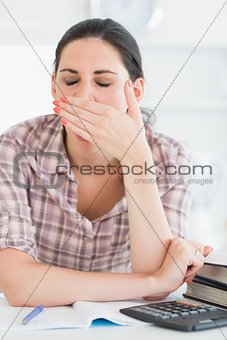 Woman yawning while doing homework