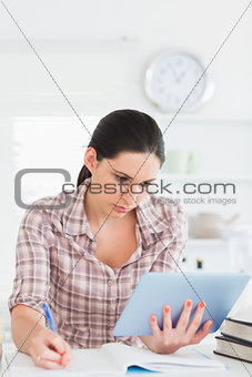 Woman holding a tablet computer while writing